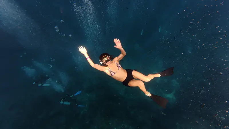 Freediver waving underwater in deep blue water