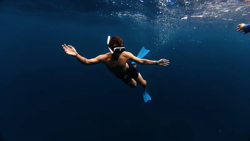 Snorkeler with arms open in blue water
